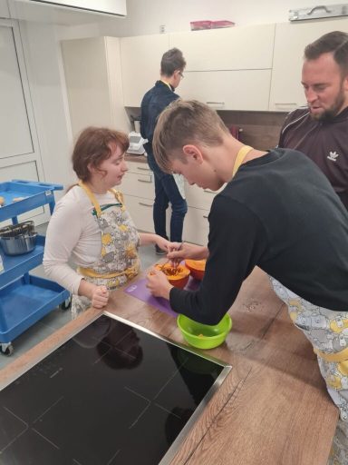 Drei Personen in einer Küche bereiten gemeinsam Lebensmittel vor.