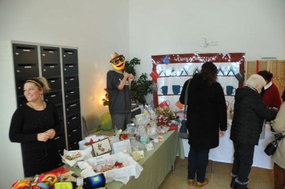 Marktstand mit dekorativen Artikeln und Menschen, die Produkte begutachten und kaufen.