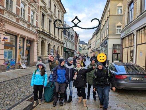 Gruppenausflug in einer belebten Straße mit historischen Gebäuden und einer fröhlichen Atmosphäre.