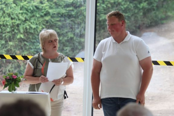 Frau spricht mit einem Mann während einer Veranstaltung, im Hintergrund Pflanzen.