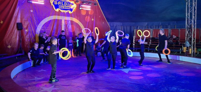 Darbietung einer Zirkusaufführung mit jugendlichen Artisten, die Reifen jonglieren.