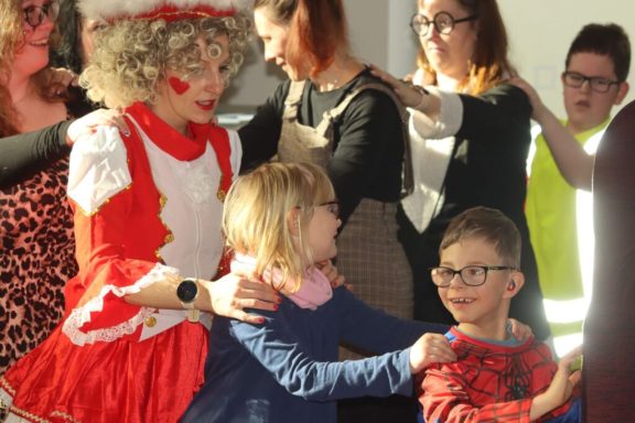 Eine Clownfigur unterhält Kinder während einer fröhlichen Veranstaltung.