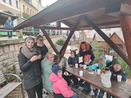 Gruppe von Menschen, die um einen Tisch unter einem Dach sitzen und warmen Tee trinken.