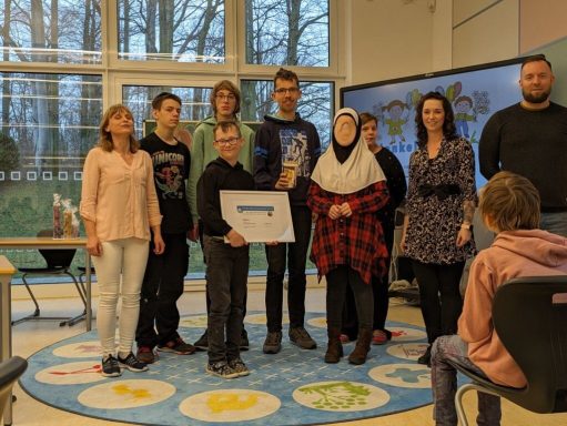 Eine Gruppe von Personen steht in einem Raum und hält eine Auszeichnung in der Hand.