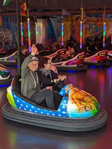 Zwei Personen in einem Autoskooter mit buntem Design und fröhlicher Stimmung.