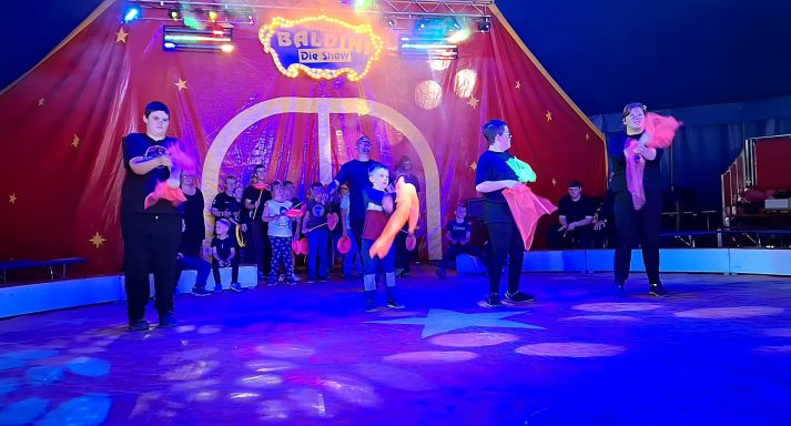 Artisten führen eine bunte Tanzaufführung in einem Zirkuszelt auf.