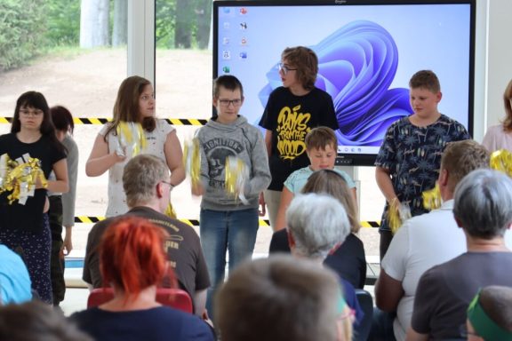 Eine Gruppe von Kindern und Jugendlichen steht auf der Bühne vor einem Publikum.