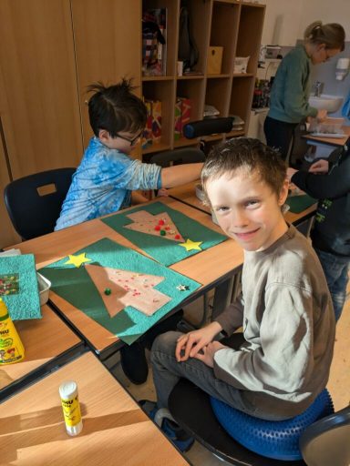 Zwei Kinder basteln an einem Tisch, einer lächelt und arbeitet an einem Kunstprojekt.