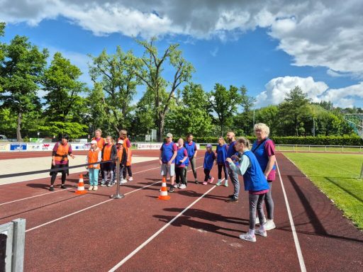 Gruppentraining auf einer Sportbahn mit Teilnehmern in Sportkleidung.