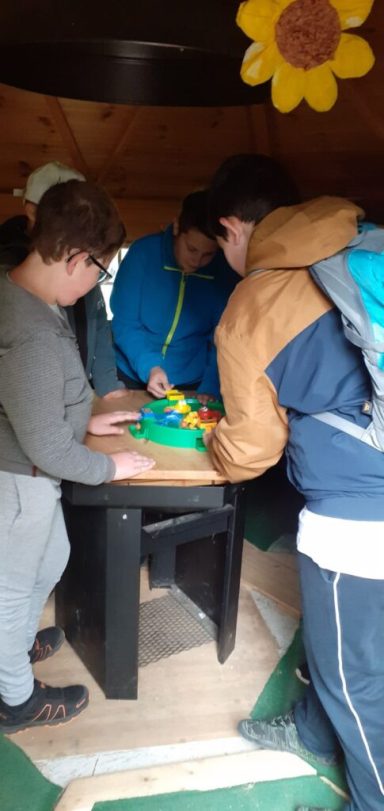 Gruppe von Personen arbeitet gemeinsam an einem Tisch mit Bastelmaterial.