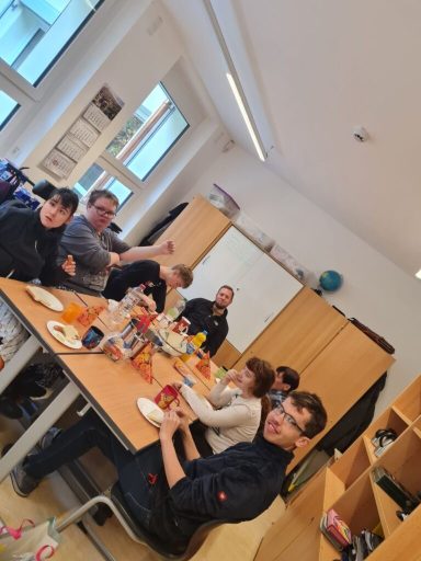 Gruppensitzung mit Snacks und Getränken in einem hellen Raum. Menschen lächeln und interagieren.