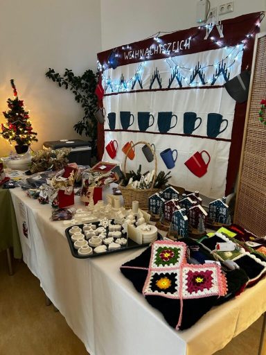 Marktstand mit Tassen, Kerzen, handgefertigten Gegenständen und dekorativen Textilien.