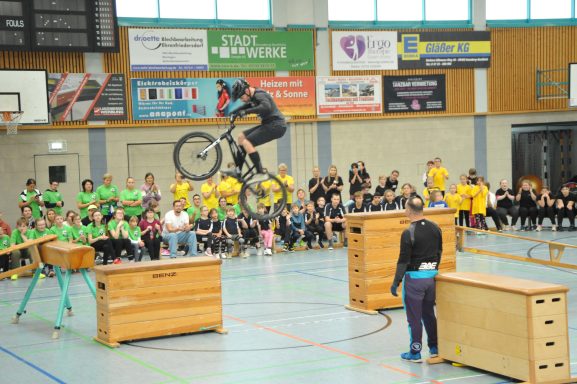 Ein BMX-Fahrer springt über Kästen, während das Publikum zuschaut.
