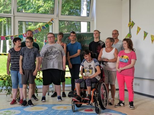 Gruppe von Menschen, einschließlich einer Person im Rollstuhl, auf einer festlichen Veranstaltung.