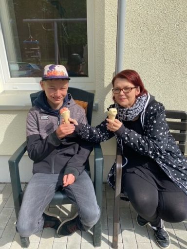 Zwei Personen sitzen mit Eiswaffeln auf einer Terrasse.