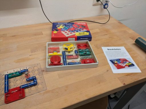 Das Spielset mit Schaltkreisen und Anleitungen liegt auf einem Tisch.