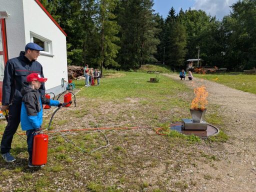 Mann und Kind üben den Umgang mit Feuerlöschern in der Natur.