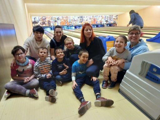 Gruppe von Kindern und Erwachsenen lächelt während des Bowlings.