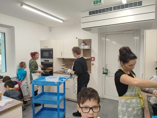 Eine Küche mit mehreren Personen, die gemeinsam kochen und an einem Tisch arbeiten.