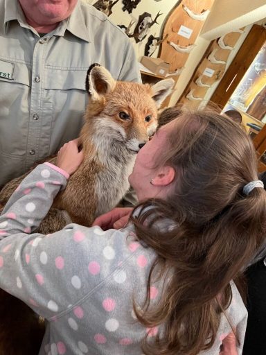 Ein Mädchen küsst einen Fuchs, während ein Mann daneben steht.