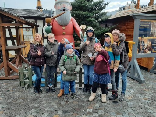 Gruppe von sieben Personen posiert fröhlich vor einer großen Weihnachtsmannfigur.
