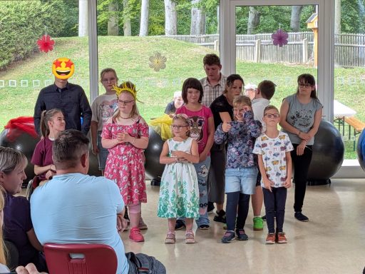 Gruppe von Kindern und Erwachsenen in einem Raum, lächelnd und kreativ gekleidet.