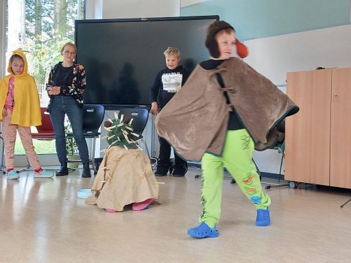 Ein Kind in einem Umhang präsentiert sich auf einer Bühne vor Publikum.