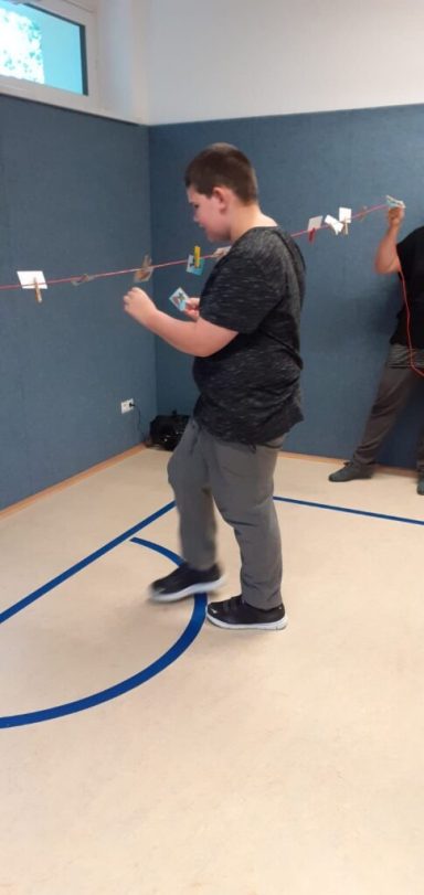 Junge steht in einem Raum und fischt mit einer Schnur nach Objekten.