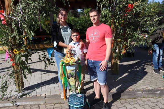 Familie steht zusammen im Freien, umgeben von bunten Blumen dekorierten Bäumen.