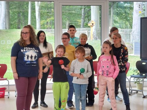 Gruppe von Kindern und Jugendlichen mit verschiedenen Requisiten in einem hellen Raum.