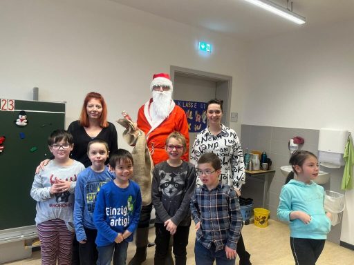 Weihnachtsfeier mit Kindern und einem Mann im Nikolauskostüm, umgeben von Erwachsenen.