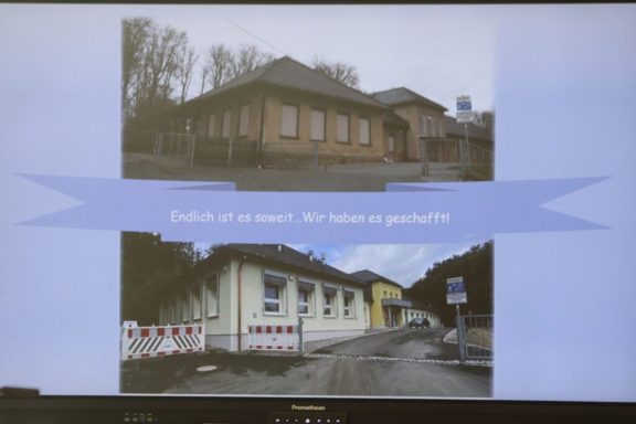 Zwei historische Gebäude, eines von vorn und eines von der Seite, mit einem Schild dazwischen.