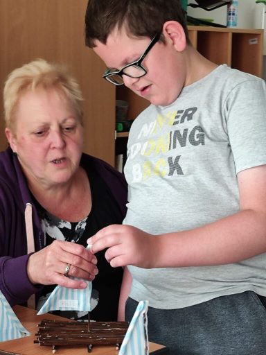 Eine Frau und ein Junge dekorieren gemeinsam einen Kuchen.