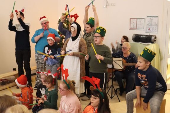 Kinder und Erwachsene in festlicher Kleidung feiern mit Musikinstrumenten und Dekorationen.