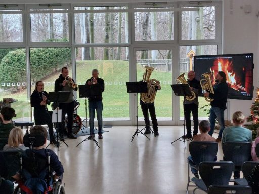 Eine Brass-Band spielt live vor einem Publikum in einem hellen Raum.