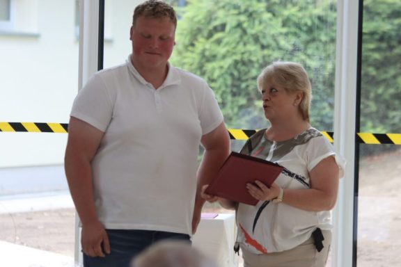 Mann und Frau stehen nebeneinander, sie hält eine Mappe, beide schauen ernst.