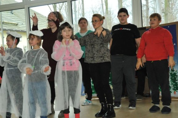 Eine Gruppe von Kindern und Erwachsenen in einem Raum, die fröhlich posieren.