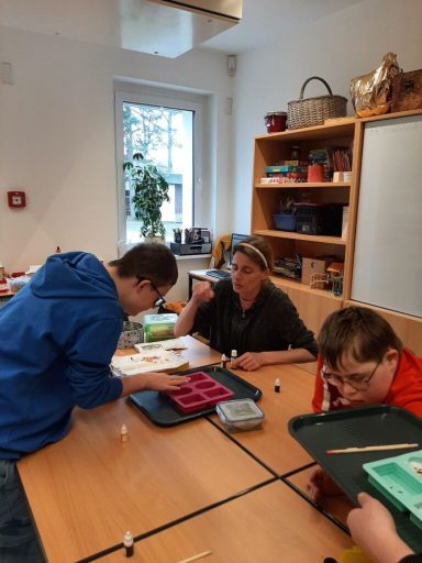 Kinder und Erwachsene arbeiten gemeinsam an einem Tisch mit Bastelmaterialien.