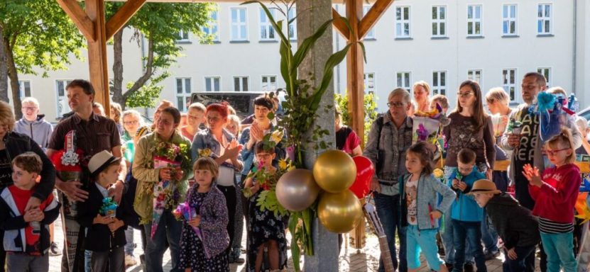 Gruppe von Kindern und Erwachsenen unter einem Vordach, feierliche Stimmung mit Dekoration.