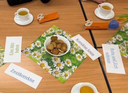 Tischgedeck mit Teetassen, Keksen in einer Schüssel und beschrifteten Platzkarten.