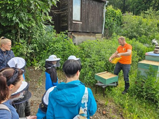 Ein Imker erklärt einem Publikum die Bienenhaltung in einem Garten.