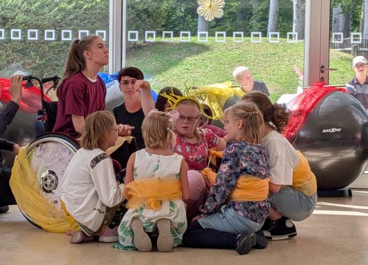 Gruppe von Kindern im Kreis, spielen und interagieren in einem hellen Raum.