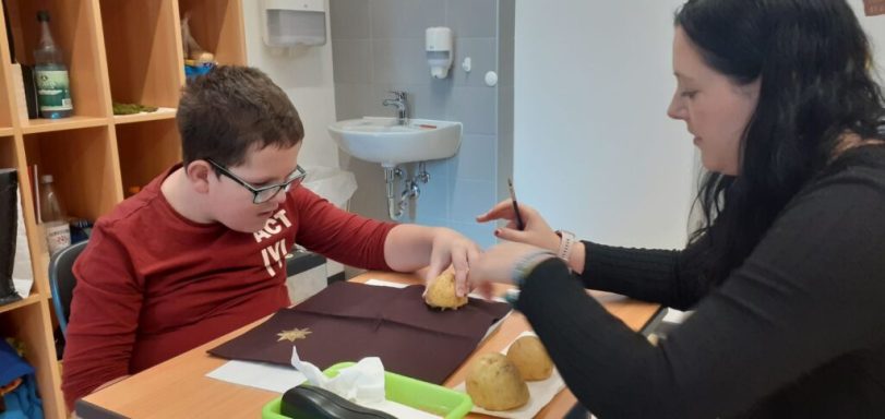 Junger Mann und Frau arbeiten gemeinsam an einer kreativen Aktivität am Tisch.