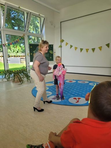 Eine Frau und ein Kind stehen auf einem bunten Teppich in einem Raum mit Fenstern.
