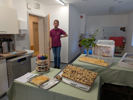 Eine Person steht neben einem Tisch mit verschiedenen Desserts in einer hellen Küche.