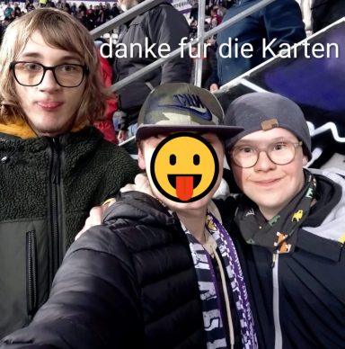 Gruppe von drei Personen lächelt in einem Stadion, mit einer Nachricht "Danke für die Karten".