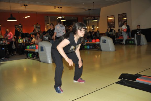 Ein Mädchen bereitet sich auf einen Wurf in einer Bowlingbahn vor.