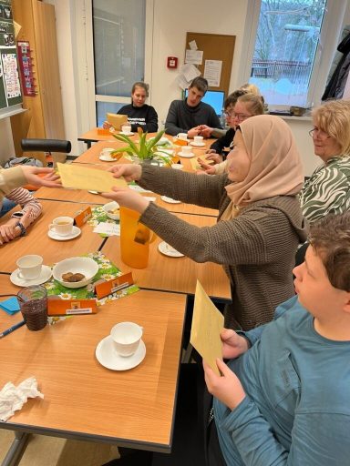 Eine Gruppe von Menschen sitzt um Tische und genießt Getränke und Snacks.