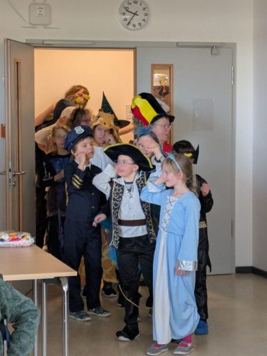 Gruppe von Kindern in Kostümen steht an einer Tür, bereit für einen Festumzug.