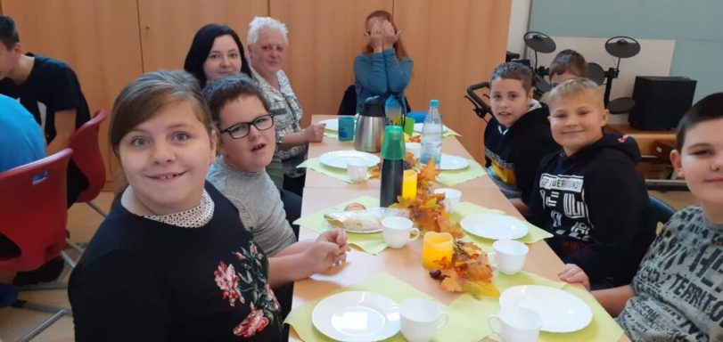 Gruppe von Kindern und Erwachsenen sitzt an einem festlich gedeckten Tisch.